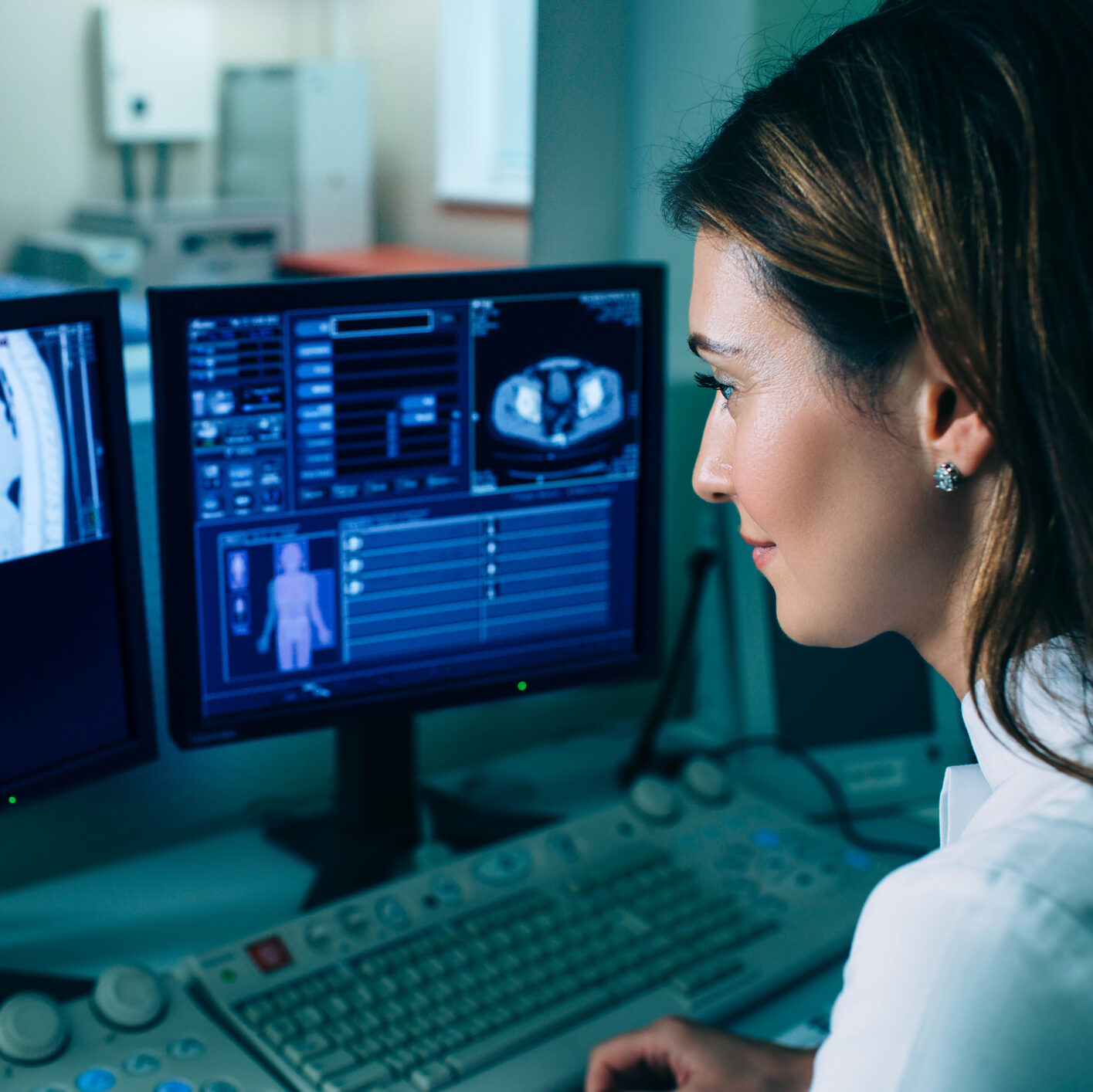 Radiologist reading a CT scan. Female doctor running CT scan from control room at hospital
